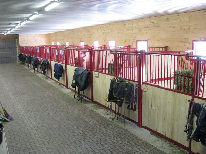 Horse stables with red railings and wooden walls.
